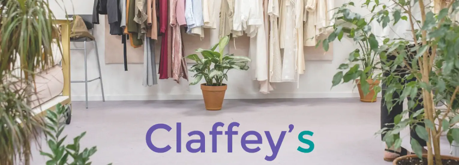 A boutique shop interior with potted plants on the floor, clothing hanging on rails in the background, and the word "Claffey’s" in large text across the bottom.