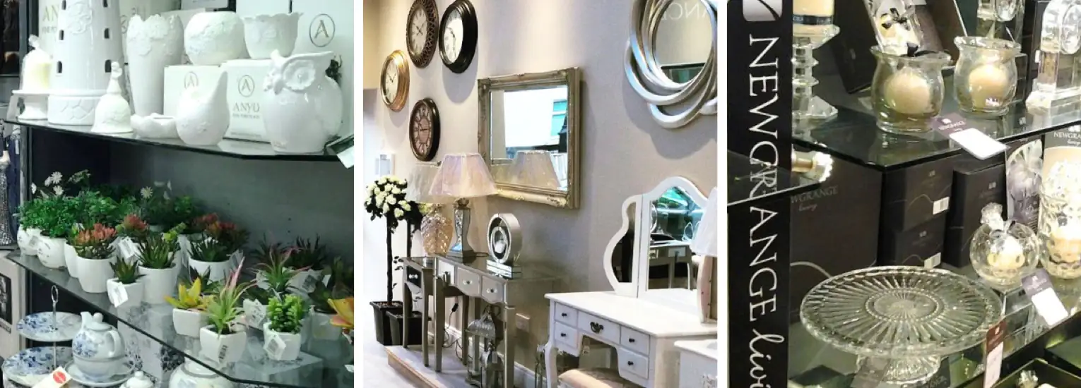 Shelves display white ceramics, potted plants, glassware, mirrors, and home decor items in a well-lit shop, with assorted decorative pieces creating a stylish, organised setting.