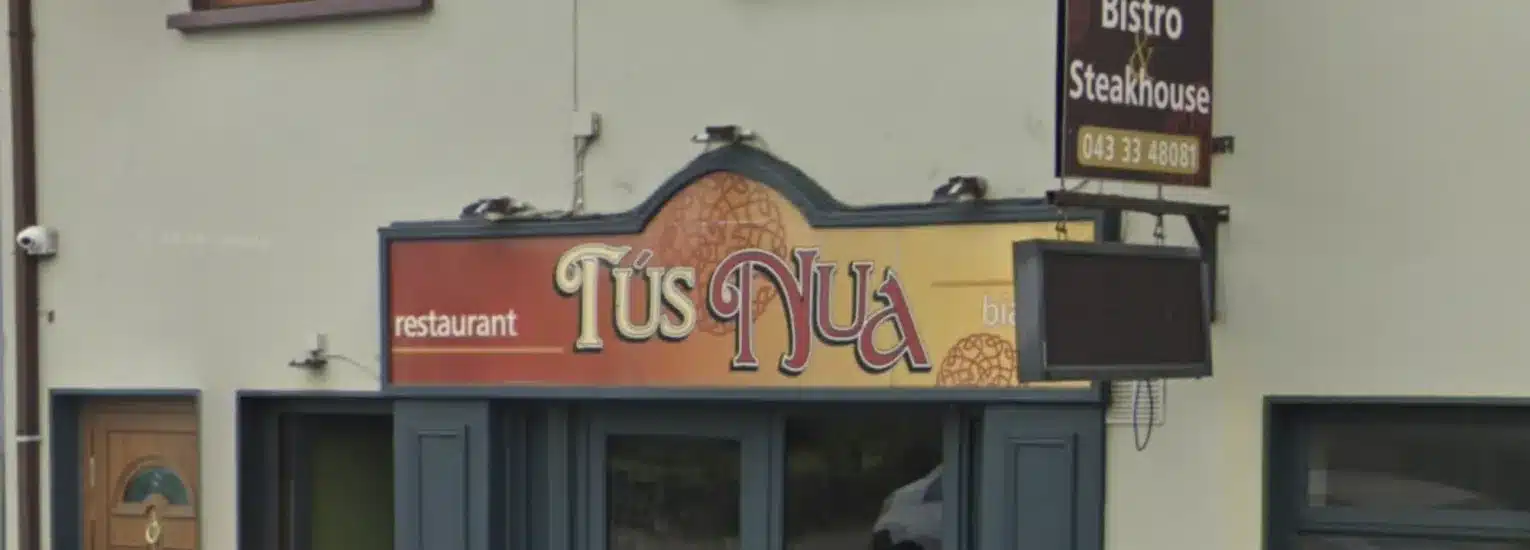 A restaurant shopfront with a sign reading "Tús Nua" in decorative font, along with "restaurant" and "bistro" on either side. Above, there is a sign for "Bistro & Steakhouse.