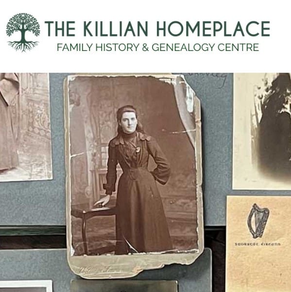 A vintage sepia photograph of a woman in a formal dress is displayed on a table, surrounded by old documents and photos. The image is part of The Killian Homeplace Family History & Genealogy Centre display.