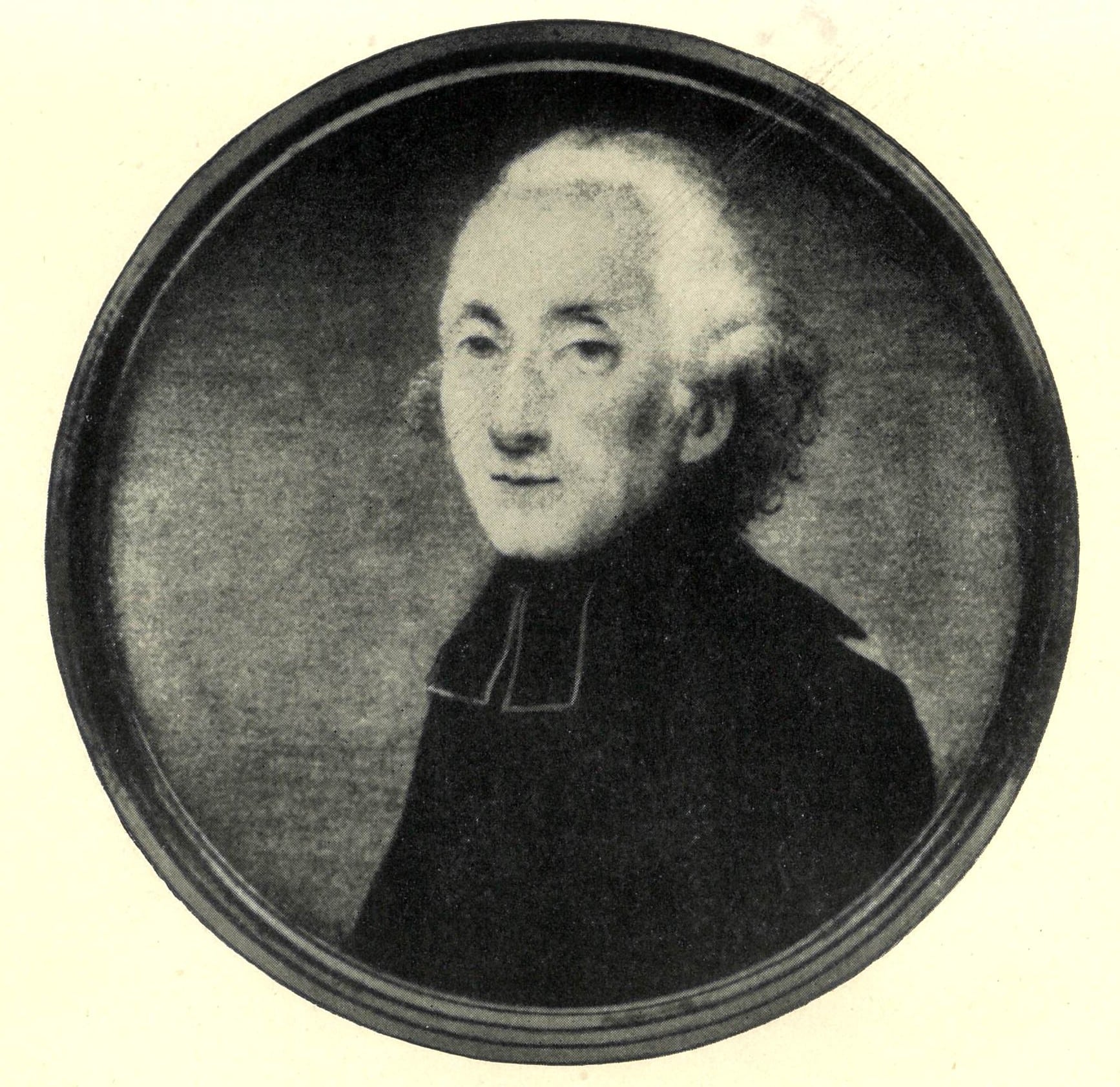 A black and white portrait of an older man with white hair, wearing dark clerical clothing, facing slightly to the left. This circular image with a plain background evokes the heritage often celebrated in Family Activities Longford.