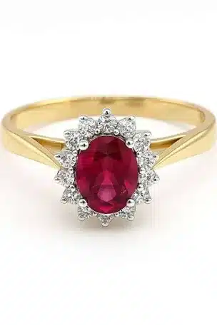 Gold ring featuring an oval red gemstone, surrounded by a halo of small round white stones, set on a simple yellow gold band.